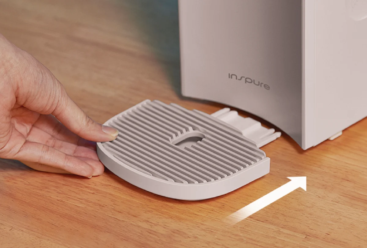 A hand attaching the detachable drip tray to the NANO+ Signature Water Purifier. (CP-AKN011)